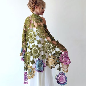 May include: A green crochet shawl with a floral design. The shawl has a fringe border and is made with a variety of colors, including purple, blue, and yellow.