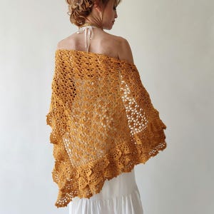 May include: A mustard yellow crochet shawl with a scalloped edge. The shawl is made with a delicate openwork pattern and has a flowing, feminine style.