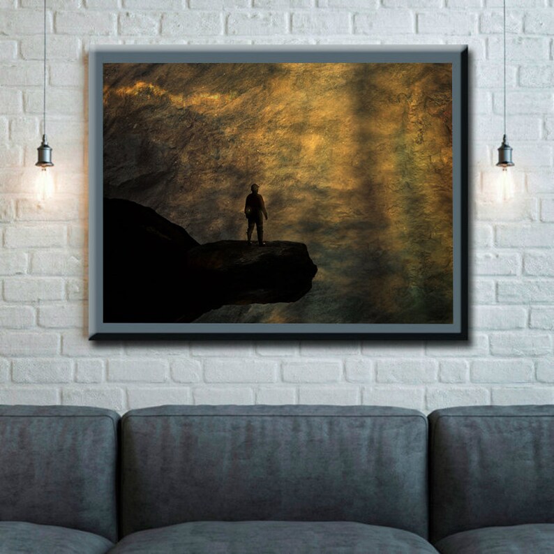 K&ouml;nnte beinhalten: Eine Silhouette einer Person, die auf einer felsigen Klippe steht und auf eine weite, goldene Landschaft blickt. Der Himmel ist voller wirbelnder Wolken, die eine dramatische und &auml;therische Atmosph&auml;re schaffen.