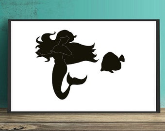 Puede incluir: Una impresión rectangular enmarcada que presenta la silueta negra de una sirena con cabello largo y fluido y un pez nadando a su lado, sobre un fondo blanco. La obra de arte está contenida dentro de un borde de marco negro fino.