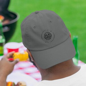 May include: A gray baseball cap with an embroidered design of a dog's head inside a circle with stars.