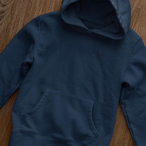 K&ouml;nnte beinhalten: Ein dunkelblauer Kapuzenpullover mit einer K&auml;ngurutasche. Der Pullover ist aus einem weichen, bequemen Stoff.