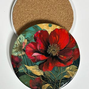 May include: Round coaster with a vibrant floral design featuring a large red flower with intricate details. The coaster has a cork backing and the text "Coaster #1". The floral design includes green and yellow accents.