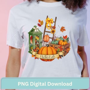 May include: A white t-shirt featuring a graphic of a green lantern, a wooden ladder with a yellow bow, a wooden crate, and various pumpkins. A banner across the bottom of the graphic displays the text Hello Fall, surrounded by autumn leaves.