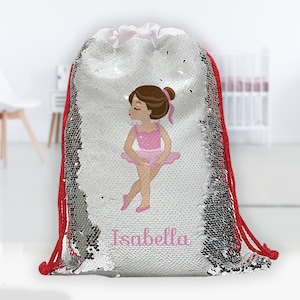 May include: A silver sequin drawstring bag with a red drawstring. The bag features a colorful illustration of a ballerina with the name "Isabella" printed below.