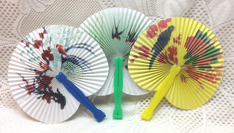 May include: Three paper folding fans with colorful designs. The fans are closed and have wooden handles. The fans are white, yellow, and green with bird and floral designs.