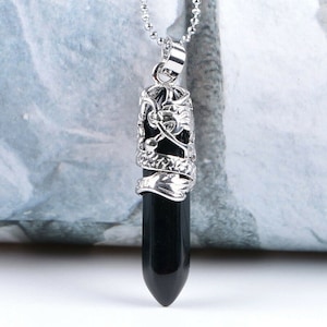 May include: A silver dragon pendant necklace with a black gemstone. The dragon is wrapped around the gemstone, which is shaped like a long, pointed teardrop.