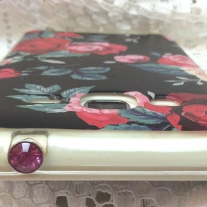 May include: A black phone case with a floral design featuring red, pink, and white roses. The case has a clear, protective layer and a pink rhinestone embellishment.