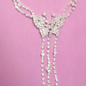 May include: A silver chain bracelet with a butterfly charm adorned with clear rhinestones. The bracelet has a delicate chain and a ring at the end.
