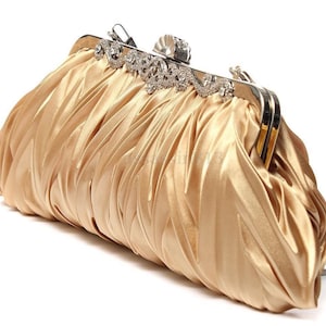May include: A gold satin clutch purse with a silver clasp and rhinestone embellishments. The purse has a chain strap.
