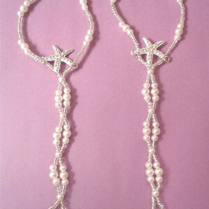 May include: Two white pearl anklets with silver starfish charms. The anklets are made with small white pearls and have a delicate design.