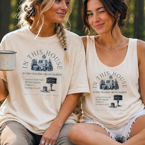 Puede incluir: Dos mujeres con camisetas color crema con el texto "IN THIS HOUSE" y un gráfico de una casa y un pastel. El texto dice "comemos pastel de chocolate para desayunar y nunca nos preocupamos por cosas tontas como la hora de acostarse o cepillarnos los dientes."