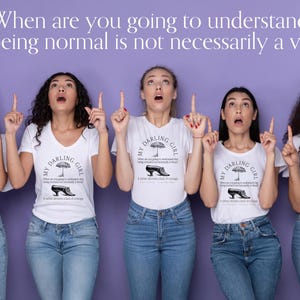 May include: Five individuals wearing white t-shirts with a graphic print featuring an umbrella, a shoe, and the text "My Darling Girl" and "When are you going to understand that being normal is not necessarily a virtue?" paired with blue jeans.