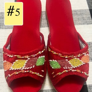 以下が含まれることがあります： 赤いベルベットのオープントゥスリッパのペア。スリッパは、オレンジ、イエロー、グリーン、レッドの色合いのビーズの葉のデザインで装飾されています。「#5」の数字が左上の黄色の長方形にあります。