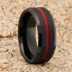 Op de afbeelding: Een zwarte ring van wolfraamcarbide met een rode streep rond de band.