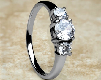 May include: A silver ring with three round clear stones. The center stone is larger than the two stones on either side.