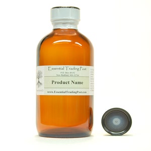 May include: A brown glass bottle with a white cap and a label that says "Essential Trading Post" and "Product Name". The bottle is sitting on a white surface. There is a black cap next to the bottle.