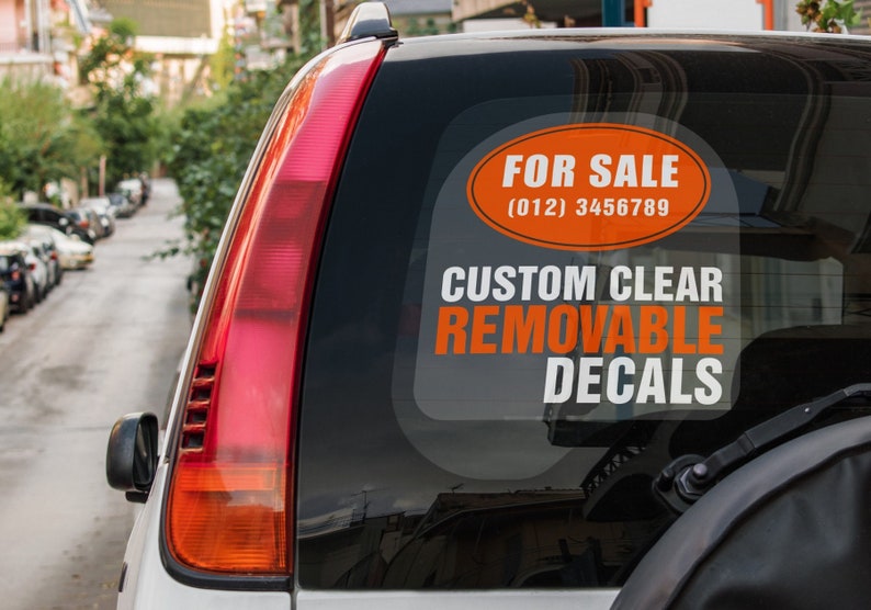 May include: A white car with a rear window sticker that says "FOR SALE (012) 3456789 CUSTOM CLEAR REMOVABLE DECALS".
