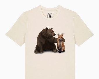May include: A beige t-shirt with a brown bear and a red fox printed on the front. The bear is sitting with its paw on the fox's shoulder.