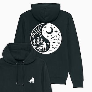May include: Black hooded sweatshirt with a white yin yang design on the back. The yin yang symbol features a wolf, mountains, trees, a crescent moon, and stars. The front of the sweatshirt has a small white wolf design on the left chest.
