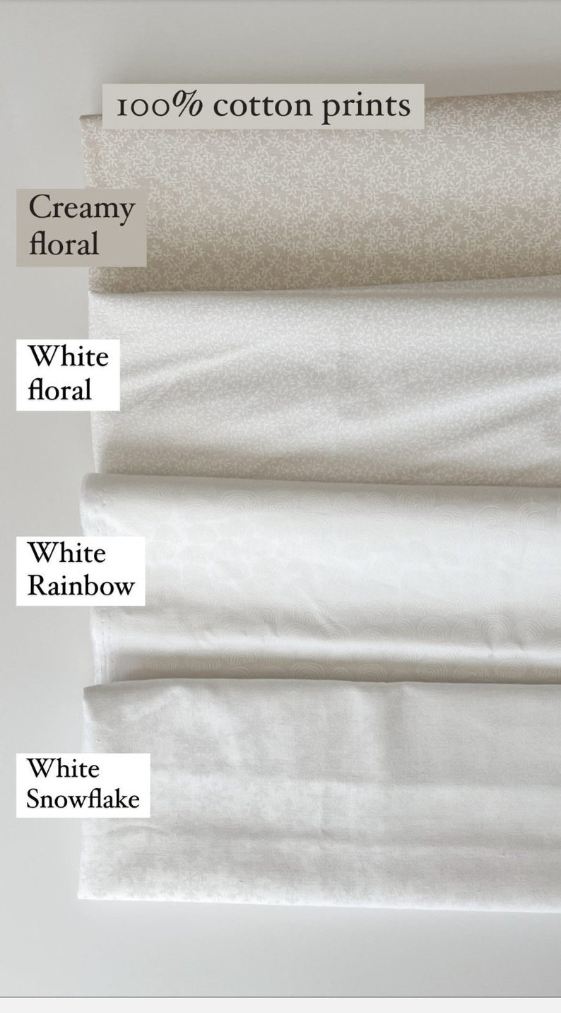 Op de afbeelding: Een stapel 100% katoenen prints in verschillende patronen. De stoffen zijn onder andere "Creamy floral", "White floral", "White Rainbow" en "White Snowflake". De stoffen zijn wit en gebroken wit.