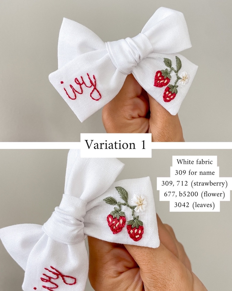 Op de afbeelding: Witte stoffen strik met rode geborduurde tekst "ivy" en een aardbeienontwerp. De strik heeft twee rode aardbeien, groene bladeren en een kleine witte bloem. Een charmant haaraccessoire.