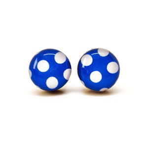May include: A pair of blue and white polka dot stud earrings. The earrings are round and have a gold setting.
