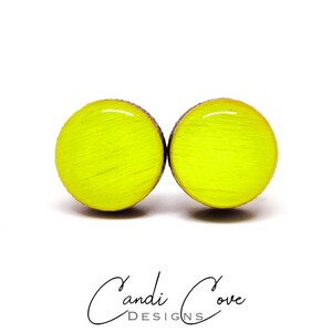 May include: A pair of bright yellow round wooden earrings. The earrings are made of wood and have a smooth, glossy finish.