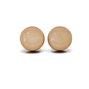 May include: A pair of round, cream-colored earrings. The earrings are made of a smooth, shiny material.