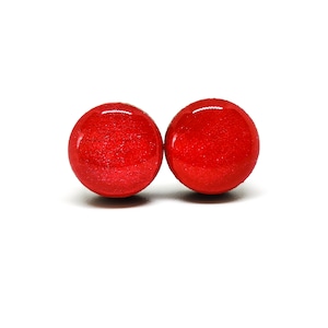 May include: A pair of red stud earrings with a sparkly finish.