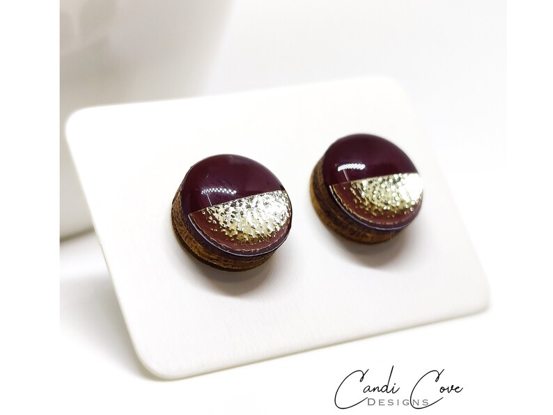 Round stud earrings with a unique two-toned design in burgundy and gold, featuring a hammered metal texture, adding a touch of edgy sophistication to any outfit. Western stud earrings by candi cove designs