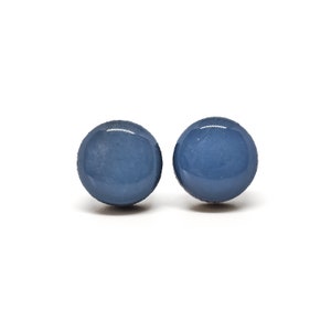 May include: Two round, blue-grey earrings with a glossy finish are displayed against a white background. The earrings are spherical and appear to be made of a smooth material.