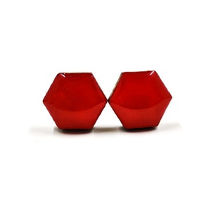 May include: A pair of red hexagonal stud earrings. The earrings are made of a shiny, glossy material.