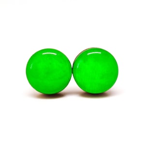 Op de afbeelding: Twee heldergroene, ronde oorbellen met een glanzende afwerking. De oorbellen staan tegen een witte achtergrond, wat hun levendige kleur en eenvoudige ontwerp benadrukt. Deze oorbellen zijn een opvallend accessoire.