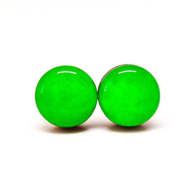 Op de afbeelding: Twee heldergroene, ronde oorbellen met een glanzende afwerking. De oorbellen staan tegen een witte achtergrond, wat hun levendige kleur en eenvoudige ontwerp benadrukt. Deze oorbellen zijn een opvallend accessoire.