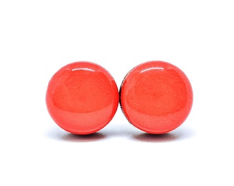 May include: A pair of bright orange round stud earrings. The earrings are made of wood and have a glossy finish.