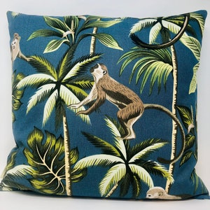 May include: A blue throw pillow with a tropical print featuring monkeys and palm trees. The pillow is made of a soft, durable fabric and is perfect for adding a touch of whimsy to any room.
