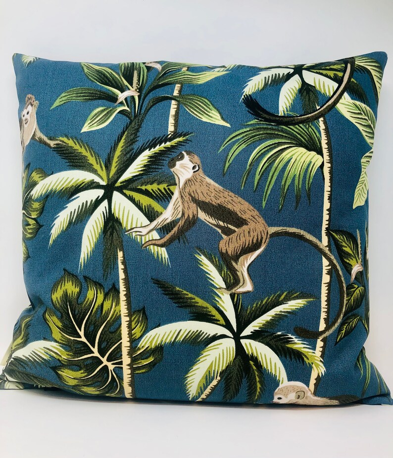 May include: A blue throw pillow with a tropical print featuring monkeys and palm trees. The pillow is made of a soft, durable fabric and is perfect for adding a touch of whimsy to any room.
