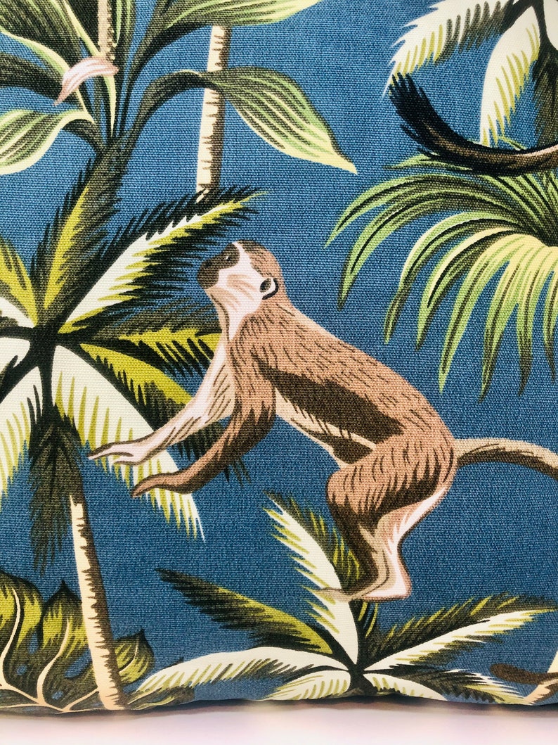 May include: A blue and green tropical print fabric with a brown monkey jumping between palm trees.