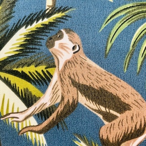 May include: A brown monkey with a white face climbing a green palm tree on a blue background.