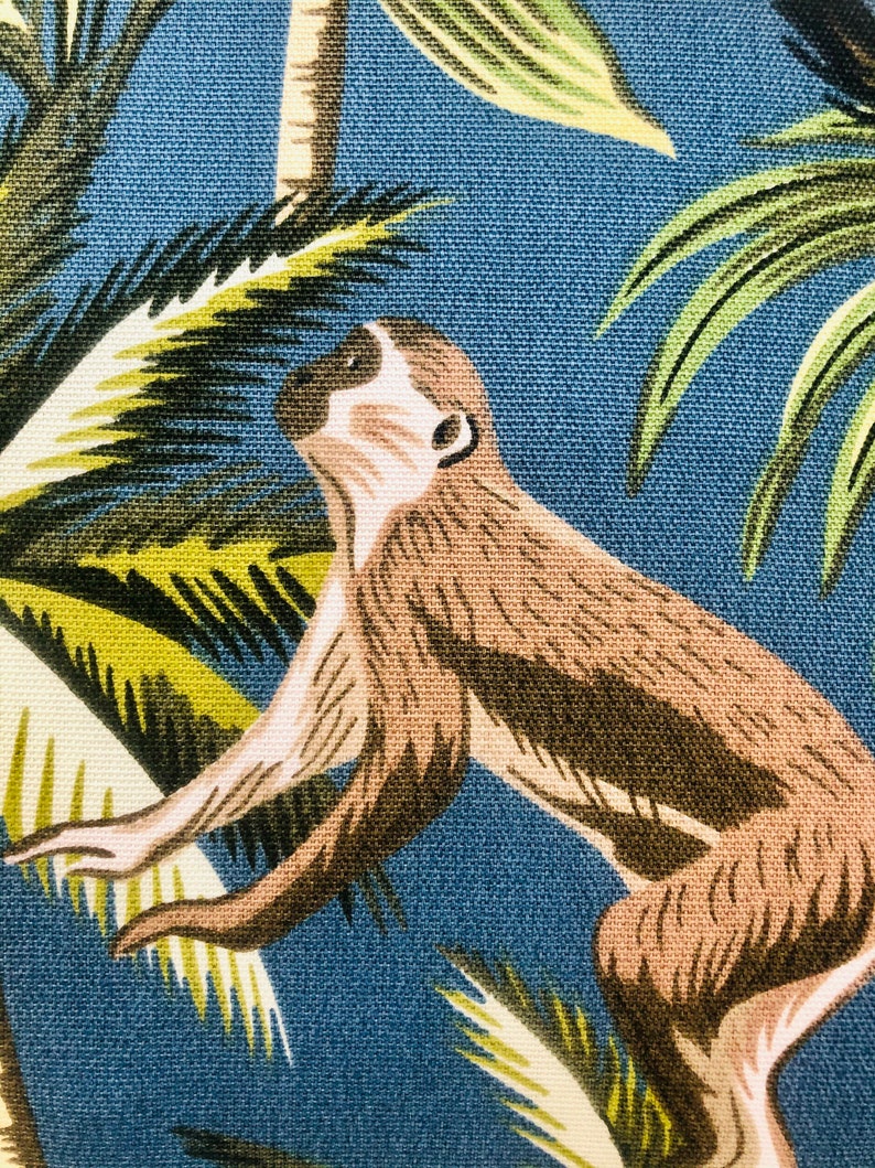 May include: A brown monkey with a white face climbing a green palm tree on a blue background.