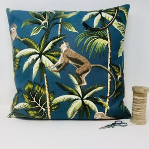 May include: A blue cushion with a tropical print featuring monkeys and palm trees. The cushion is made of a soft, durable fabric and is perfect for adding a touch of nature to any room.