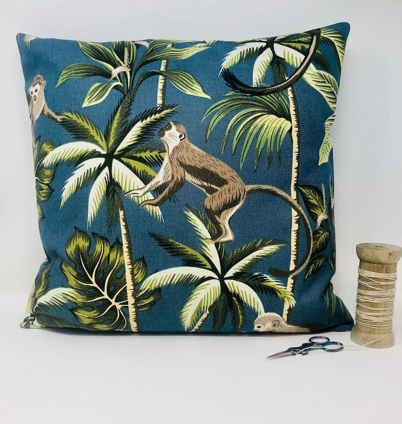 May include: A blue throw pillow with a tropical print featuring monkeys and palm trees. The pillow is made of a soft, durable fabric and is perfect for adding a touch of nature to any room.