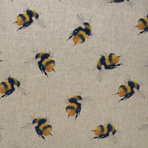 May include: A beige fabric with a repeating pattern of yellow and black bumblebees. The bees are flying in different directions.