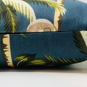 May include: A blue throw pillow with a tropical palm tree print. The pillow has a zipper closure.