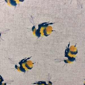 May include: A beige fabric with a repeating pattern of black and yellow bumblebees. The bees are painted in a watercolor style and are flying in different directions.