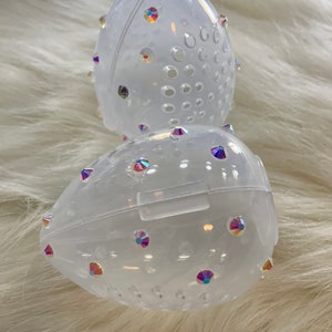 May include: Two clear plastic egg-shaped containers with a pattern of small holes and iridescent rhinestones.