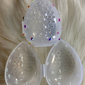 May include: Three clear plastic makeup sponge holders with a mesh design and rhinestones. The holders are shaped like a teardrop.
