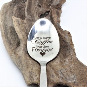 May include: A silver spoon engraved with the words "Let's have coffee together forever". A small heart is engraved below the text.