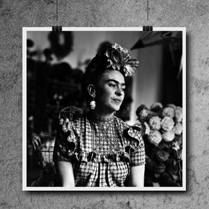 May include: Black and white portrait photograph of Frida Kahlo wearing a flower crown and a plaid blouse. She is looking to the right of the frame.